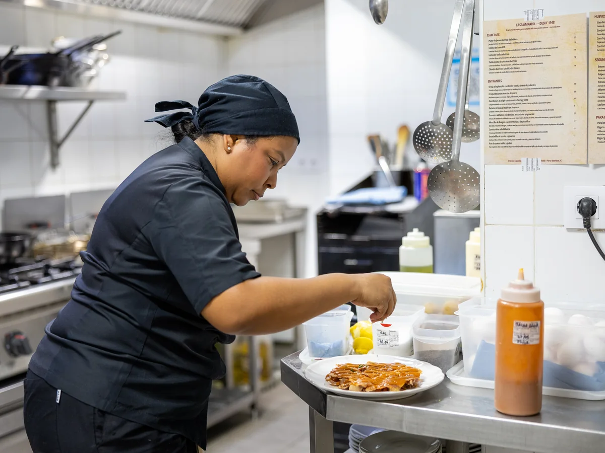 Cocinera de Casa Amparo emplatando un plato en la cocina